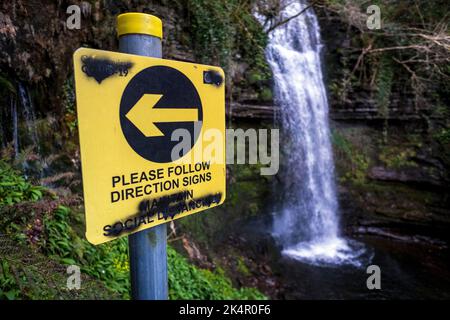 Vandalizzato segno chiedendo escursionisti a distanza sociale, Glencar Waterfall, County Leitrim, Irlanda Foto Stock