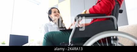 Donna in sedia a rotelle comunica con un amico a casa primo piano Foto Stock