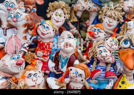 Figure di argilla fatte a mano in un negozio di souvenir. Mostra con molte bambole e animali di argilla. Figurine alla fiera sul banco nel negozio. Foto Stock