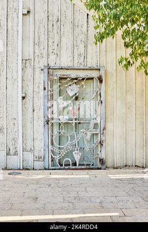 Porta in metallo fatta di figure diverse all'ingresso della casa in legno di legno grezzo Foto Stock