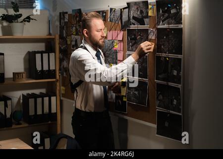 Detective guardando la scheda prove in ufficio, indizi e Blueprints su fango bordo di investigatore, agenzia privata detective Foto Stock