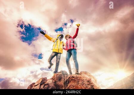 Coppia di giovani escursionisti che si esaltano in cima alle braccia di montagna - coppia multietnica di amici che si divertono a fare trekking al tramonto - natura e peo Foto Stock