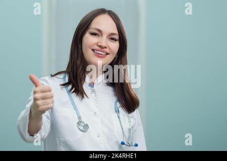 Allegro pediatra sorride mostrando un gesto OK con le mani Foto Stock
