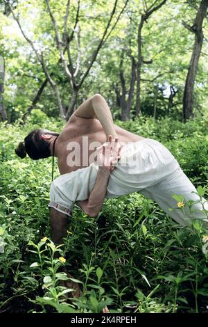 L'uomo caucasico in abbigliamento sportivo che fa yoga pone in natura. Yoga all'aperto Foto Stock