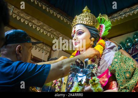 Un uomo che decora un idolo di Maa Durga in un mandal a Mumbai per l'auspicious festival indiano di Navratri Foto Stock