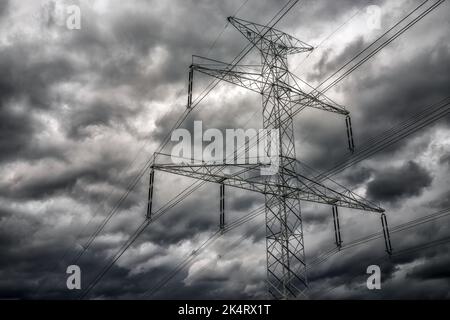Polo ad alta tensione e nuvole scure sul cielo. Foto Stock