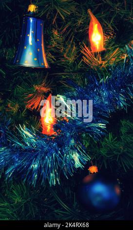 Luce di Natale che splana sull'albero di natale decorato con palla blu e campana. Foto Stock