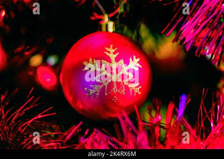 Palla di Natale rossa su un albero di Natale decorato. Foto Stock
