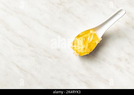 Capsule di olio di pesce. Omega 3 pillole gialle in cucchiaio sul tavolo bianco. Vista dall'alto. Foto Stock