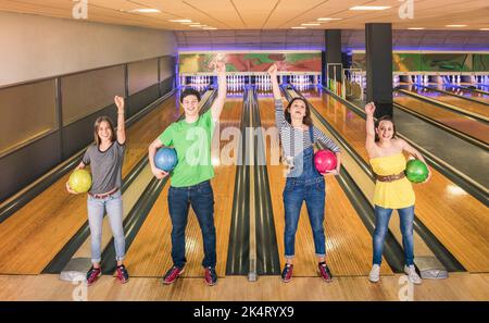 I migliori amici in posa in posizione di vittoria alla pista da bowling guardando la macchina fotografica - amicizia e concetto di hobby con i giovani giocosi che hanno divertimento e sha Foto Stock