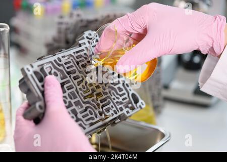 L'assistente di laboratorio versa un liquido giallo, esperienza Foto Stock