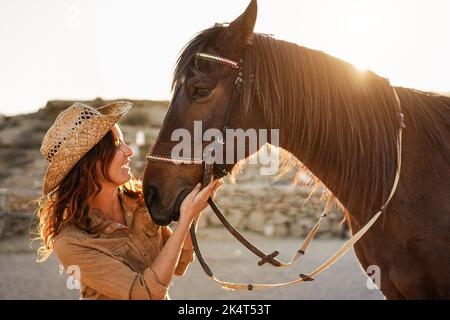 Giovane contadina che si diverte con il suo cavallo al ranch della fattoria - Focus principale sull'occhio del cavallo. Foto Stock