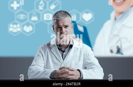 Scienziato medico che dà un discorso, icone mediche e schermo in background Foto Stock