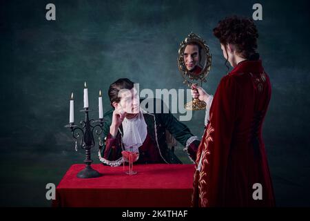 Ritratto di donna a immagine di vampiro guardando in specchio per vedere la sua infinita giovinezza. Maschio che guarda la donna. Famiglia immortale Foto Stock