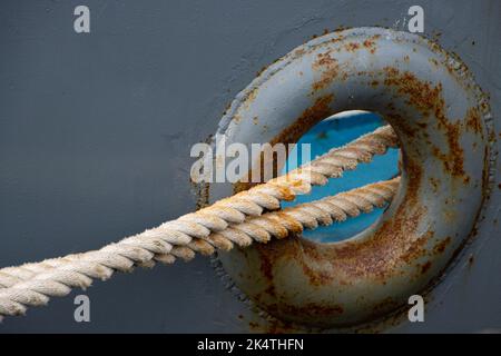 Primo piano di una corda di ormeggio attraverso un foro in una barca arrugginita Foto Stock