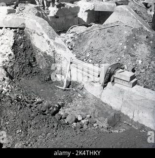 anni '1950, sito storico di demolizione di edifici, lavori di costruzione, un piccone e una giacca da operaio, operaio in pausa. Foto Stock