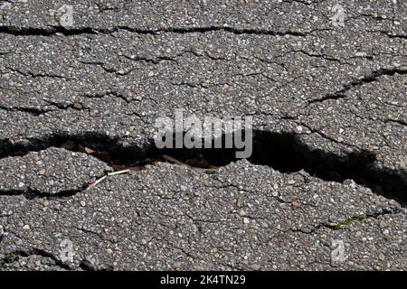 Spaccatura su vecchia strada asfaltata usurata per lo sfondo Foto Stock