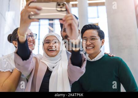 Gruppo di lavoro multietnico che prende un autoritratto in ufficio Foto Stock