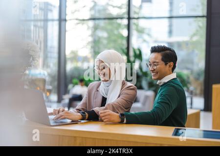Giovane coppia di business utilizzando computer portatile in ufficio Foto Stock