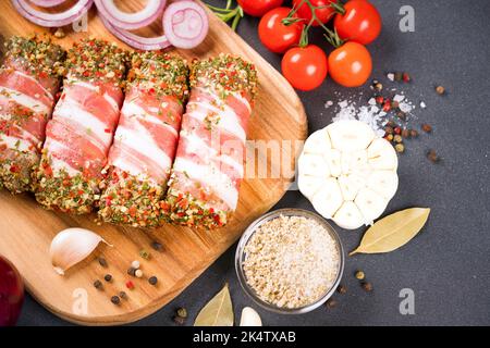 Vista in primo piano di cevapcici balcanici o romeno mitigtei. Cibo tradizionale balcanico. Involtini di carne cruda macinata avvolti con pancetta con condimenti e verdure Foto Stock