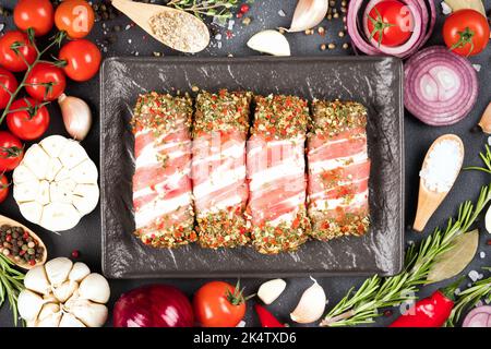 Cibo tradizionale balcanico - cevapcici fatti in casa o romeno mitigtei pronti per barbecue. Involtini di carne cruda macinata avvolti con pancetta con condimenti e verdure Foto Stock