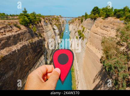 La mano di un uomo con un marcatore rosso che punta sul canale di Corinto, in Grecia, da Isthmia, in un giorno d'estate Foto Stock