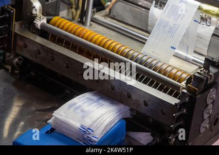 Primo piano di una macchina che stampa etichette per siringhe in un magazzino di produzione medica Foto Stock