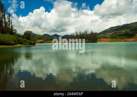 Montagne torreggianti, fiume con piccola isola visibile, cielo blu e bianco, riflesso visibile in acqua, il dono della natura di verde ovunque è la strada Foto Stock