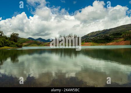 Montagne torreggianti, fiume con piccola isola visibile, cielo blu e bianco, riflesso visibile in acqua, il dono della natura di verde ovunque è la strada Foto Stock