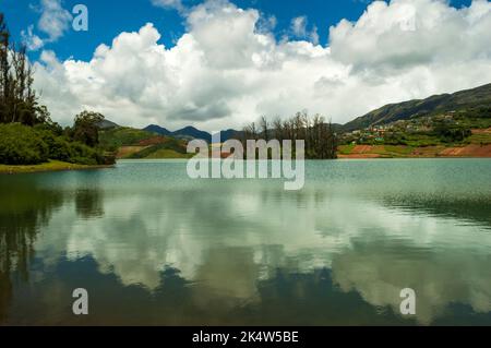 Montagne torreggianti, fiume con piccola isola visibile, cielo blu e bianco, riflesso visibile in acqua, il dono della natura di verde ovunque è la strada Foto Stock