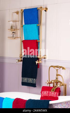 Una foto verticale di colorati asciugamani di bambù appesi su una rastrelliera dorata in un bagno Foto Stock