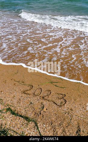 2023 scritto sulla spiaggia. Onde di mare verde turchese con schiuma. Concetto turistico per le vacanze di Capodanno. Struttura naturale. Modello poster Foto Stock