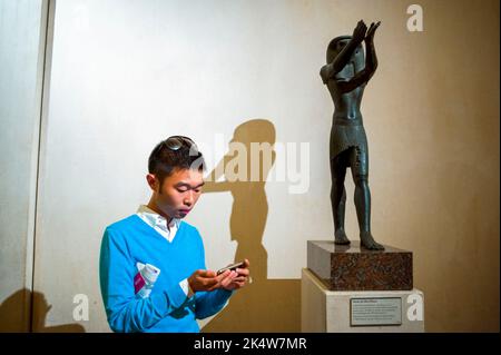 Parigi, Francia, giovane turista cinese Invio di messaggi di testo su smartphone, iPhone, all'interno della Galleria d'Arte delle Antichità egizie del Museo del Louvre, "Statua di Horus god", arte della civiltà antica, Museo Egizio Foto Stock
