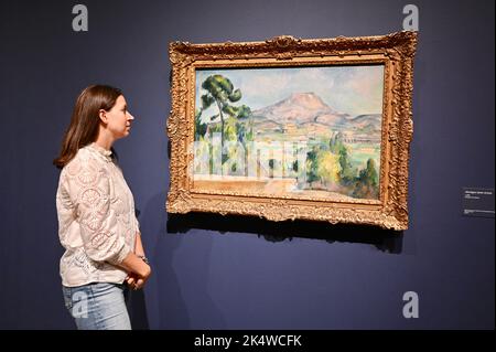 Un dipendente della galleria vede 'Montagne Sainte-Victoire' c1890. Cezanne. The EY Exhibition, Tate Modern, Bankside, Londra. REGNO UNITO Foto Stock