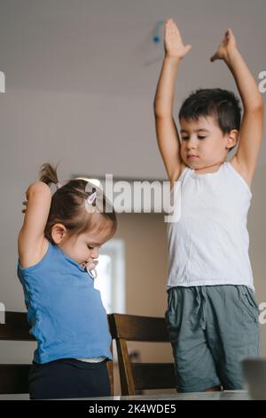 Due bambini aspettano impazientemente in cucina la madre per portare gli ingredienti in modo che possano iniziare a prepararsi per Natale. Mangiare sano Foto Stock