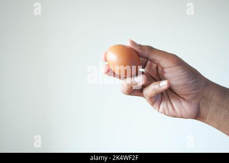 uomini che tengono un uovo contro il muro bianco Foto Stock