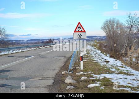 Segnale stradale che avverte il conducente che la strada è scivolosa in caso di neve Foto Stock