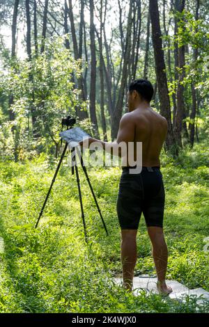 Un ragazzo con un tablet che fa video blog al telefono. Persona isolata che dà lezioni online. Uomo che dà lezioni on-line con il telefono. Foto Stock