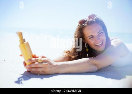 donna felice ed elegante di mezza età con spf che posa in spiaggia. Foto Stock