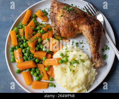 Piatto con pasto sano. Coscia di pollo arrosto con piselli e carote. Servito con purè di patate. Cucinato in casa Foto Stock