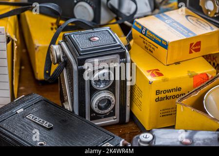 Una fotocamera reflex a doppia lente Kodak vintage al centro circondata da altri materiali di consumo Kodak e vista parziale di altre fotocamere, tutte raggruppate insieme Foto Stock