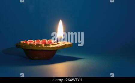 Diwali, Deepavali Hindu Festival di luci celebrazione. Spia dell'olio DIYA accesa su sfondo blu. Modello di vacanza indiano Foto Stock