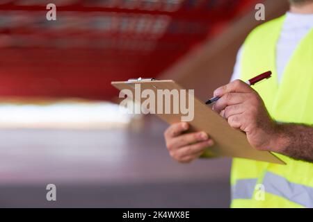 Spazio di copia. Primo piano delle mani di un uomo irriconoscibile e prendere appunti presso lo stabilimento industriale, su carta. Foto Stock