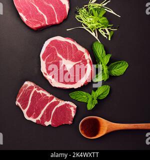 Vista dall'alto della bistecca di manzo cruda sul tavolo con condimento. Foto Stock