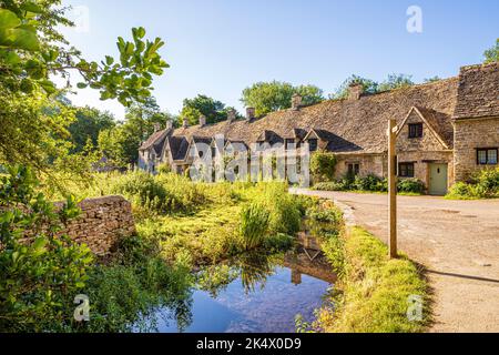 La mattina presto la luce a metà estate su Arlington Row nel villaggio Cotswold di Bibury, Gloucestershire, Inghilterra UK Foto Stock