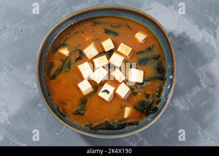 Minestra giapponese di miso in una ciotola grigia sul tavolo nero. Vista orizzontale dall'alto Foto Stock