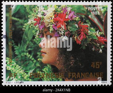 Giovane donna adornata da fiori su francobollo polinesiano Foto Stock