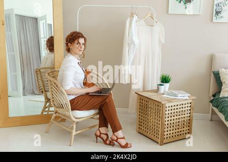 Una donna d'affari con un notebook. Uno specialista di design umano lavora a casa su un notebook. Lavoro da casa durante l'epidemia. Foto Stock