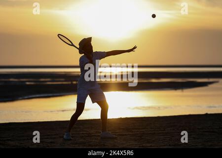 Silhouette di un giocatore di tennis retrò sulla spiaggia al sole serale sull'isola di Borkum, Germania. Foto Stock