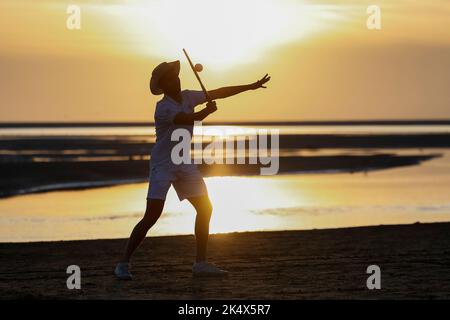 Silhouette di un giocatore di tennis retrò sulla spiaggia al sole serale sull'isola di Borkum, Germania. Foto Stock